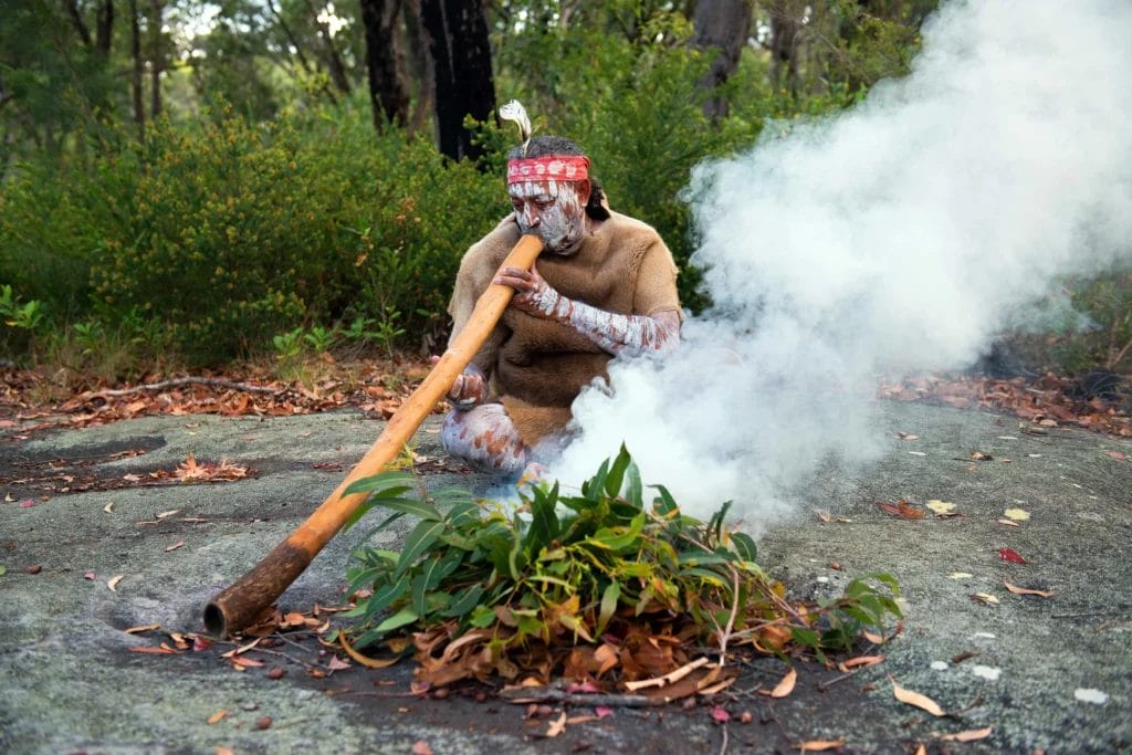 Aboriginal performer conducting a smoking ceremony as part of a Welcome to Country.
