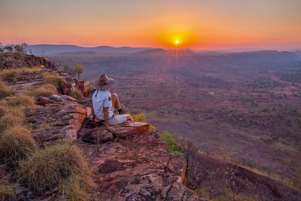 Person overlooking a vast Kimberley landscape at sunset.