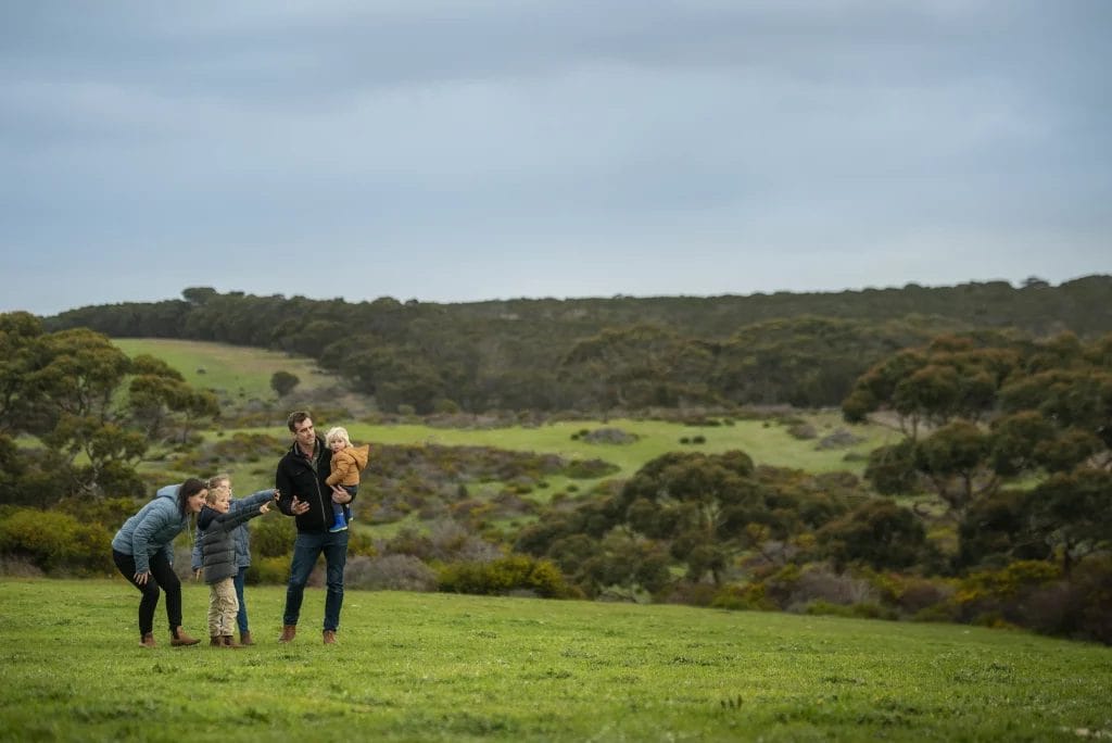 Family with three children exploring a green landscape on Kangaroo Island.