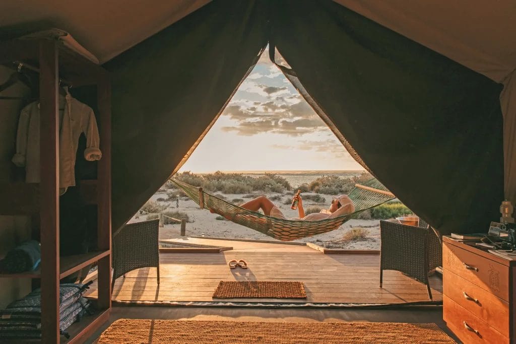 Interior view of guest lounging on hammock on the front deck of the beach-facing eco-tent at Sal Salis, Ningaloo Reef