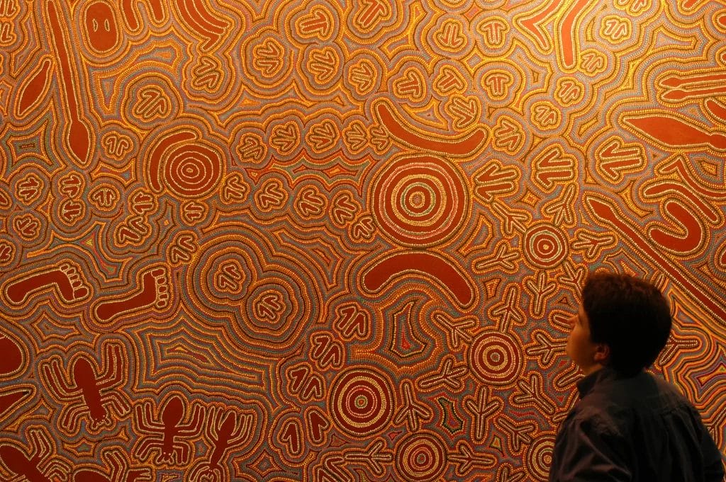 Person standing in front of a large Aboriginal dot painting in the South Australian Museum