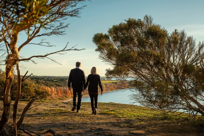 Couple walking hand-in-hand in late afternoon light in bush near Nepean Bay, Kangaroo Island