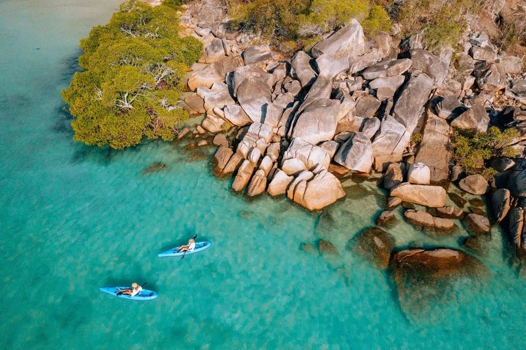 Two people in kayaks resting on clear blue water