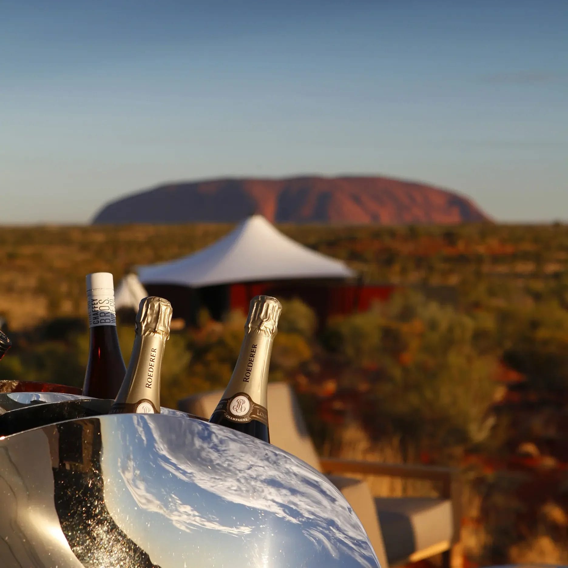 Bottles of champagne in a wine cooler overlooking Uluru in the Northern Territory