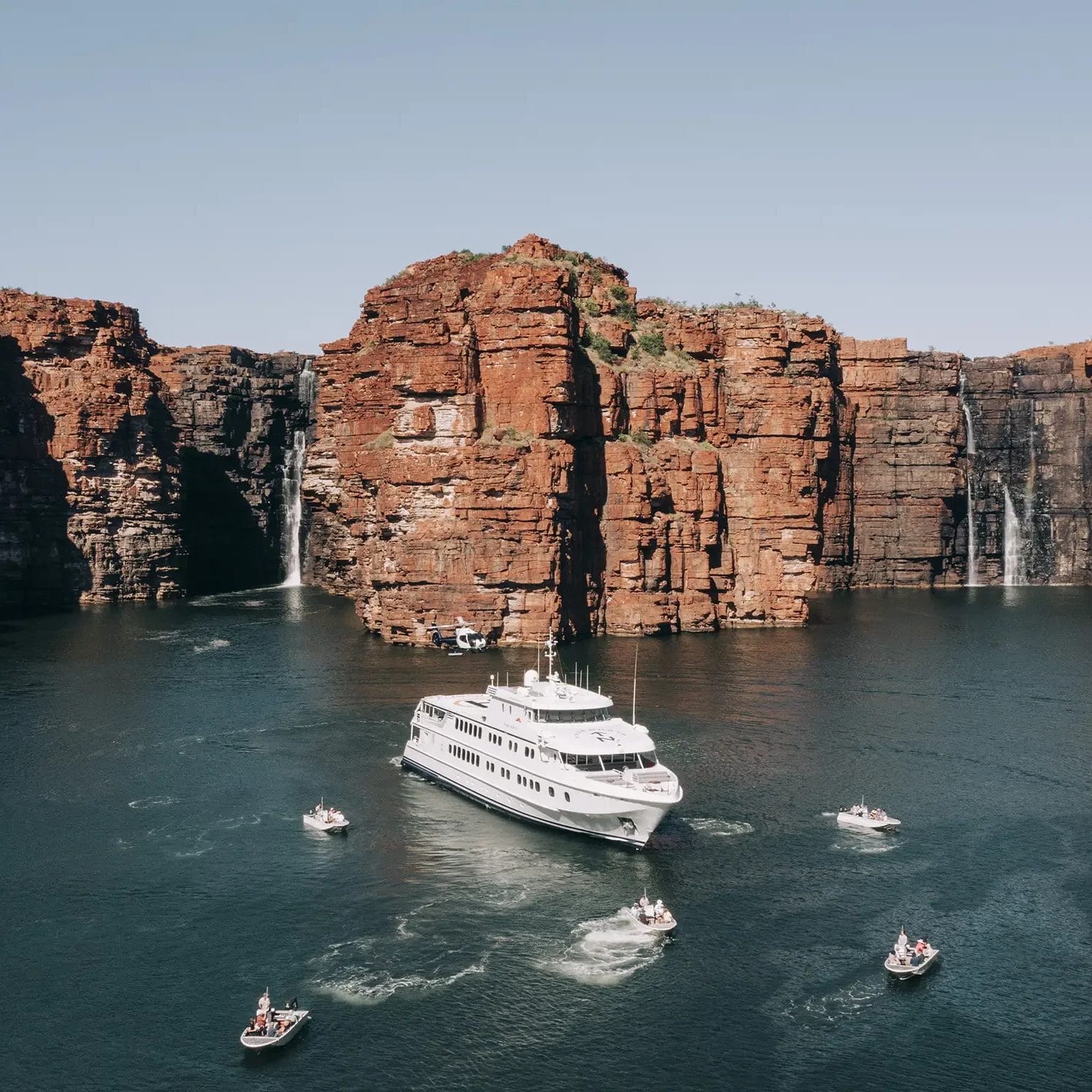 Landscape of the True North vessel and full fleet of tenders and helicopter at King George Falls, Kimberley, Western Australia
