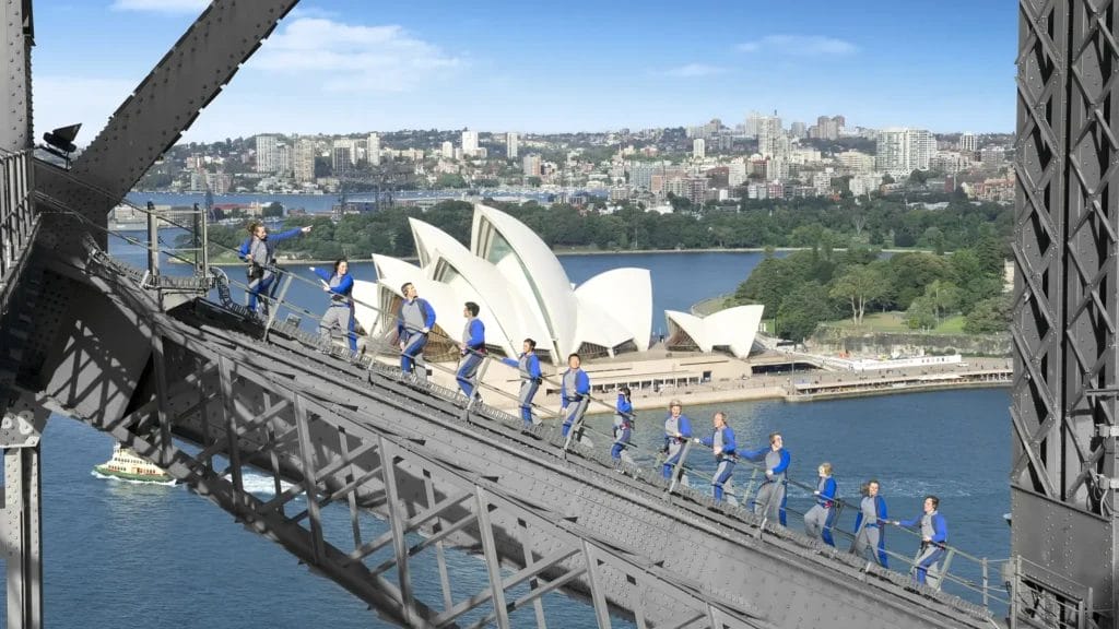 A group of people climbing the Sydney Harbour Bridge with the Opera House in the background