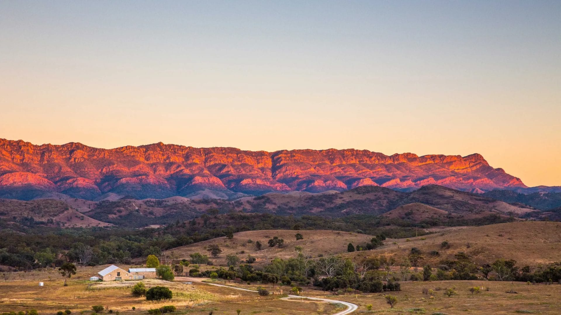 Landscape shot of Arkaba Homestead in the Flinders Ranges at dusk with the mountain range lit up in orange hues