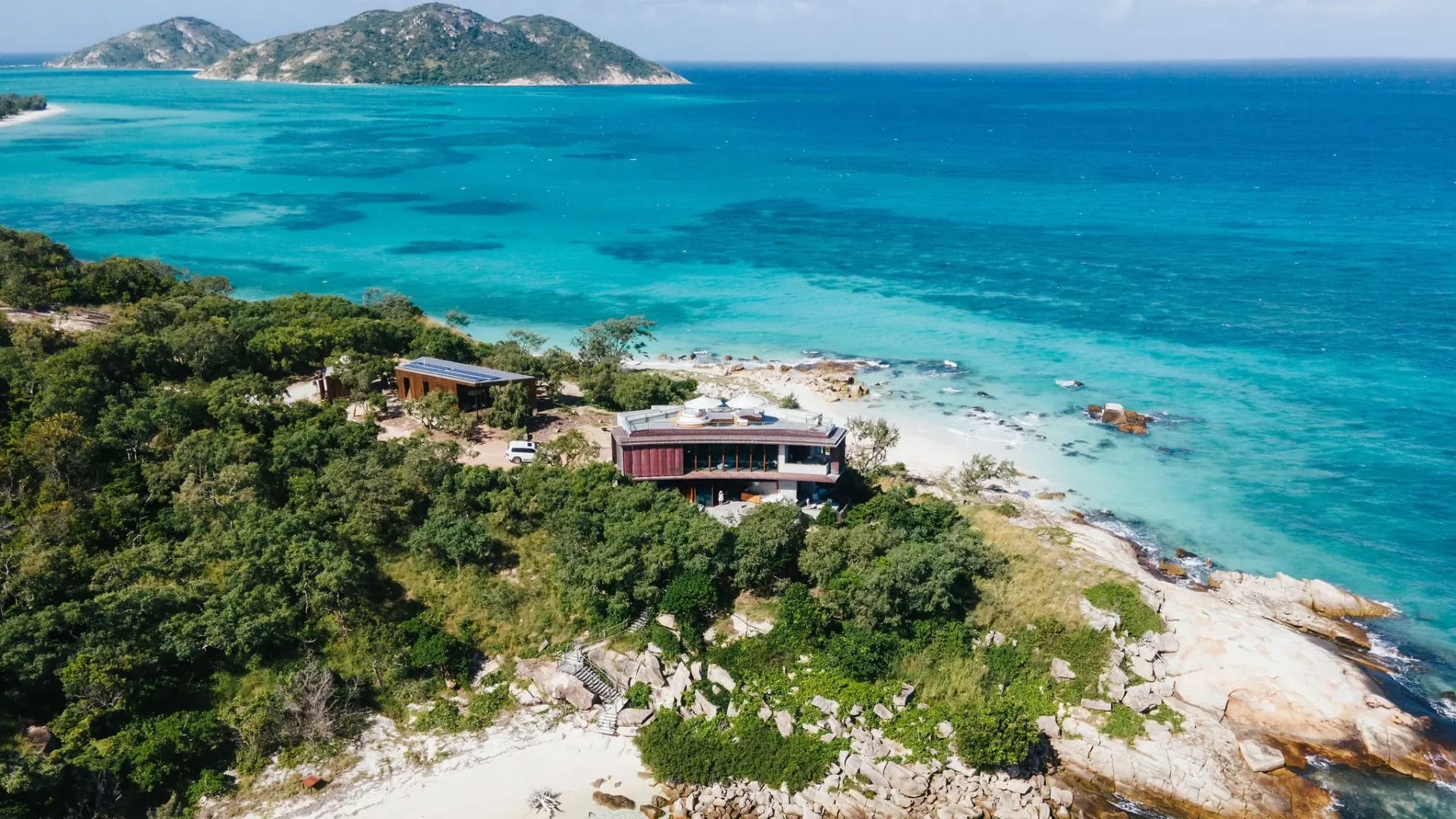 Exterior aerial of the remote House at Lizard Island amongst green bushland, white sand beaches and blue ocean